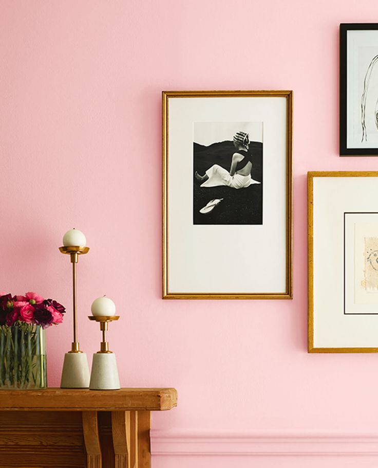 pink walls with pictures and vases on the table