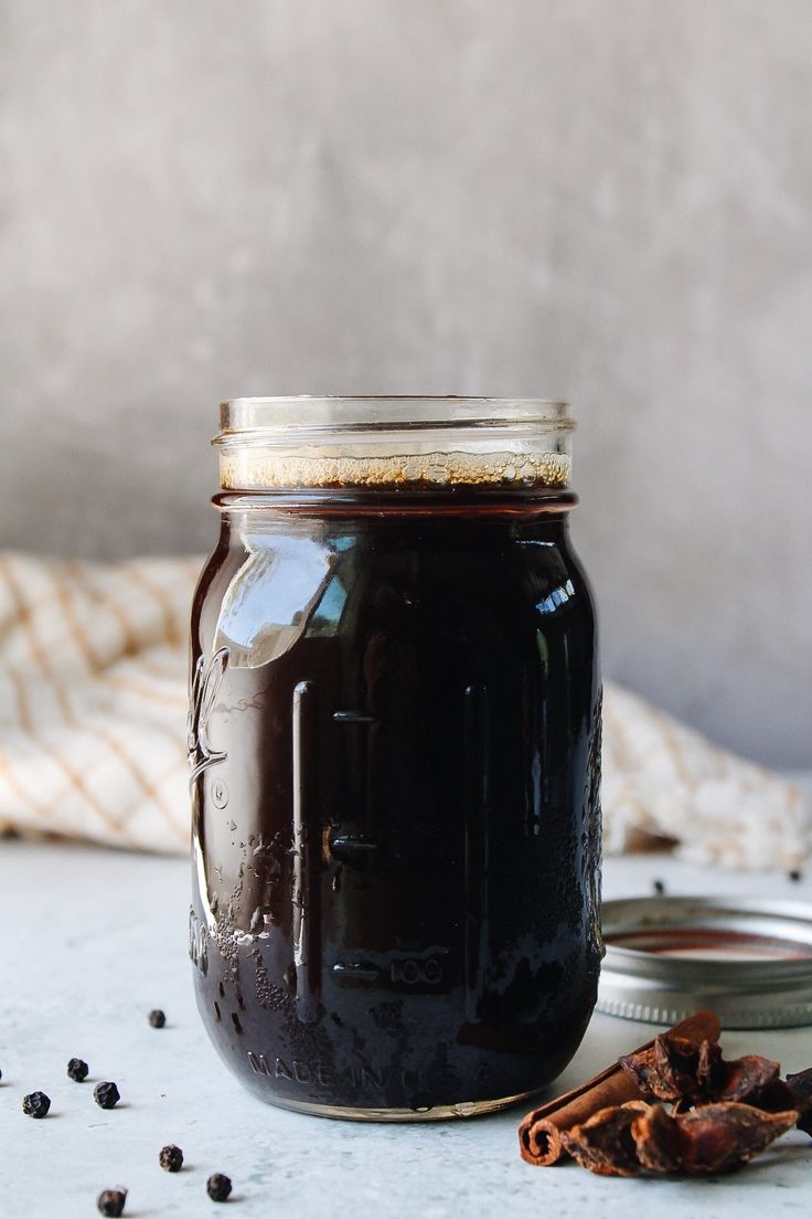 a glass jar filled with liquid next to some spices