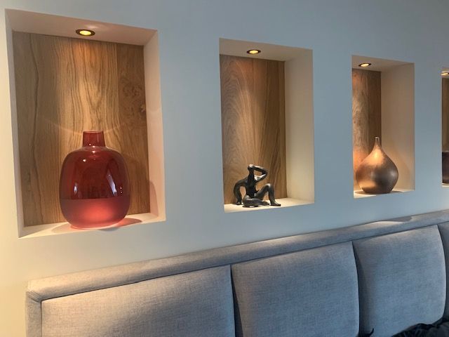 three vases are on display in the corner of a room that is white and has blue upholstered walls