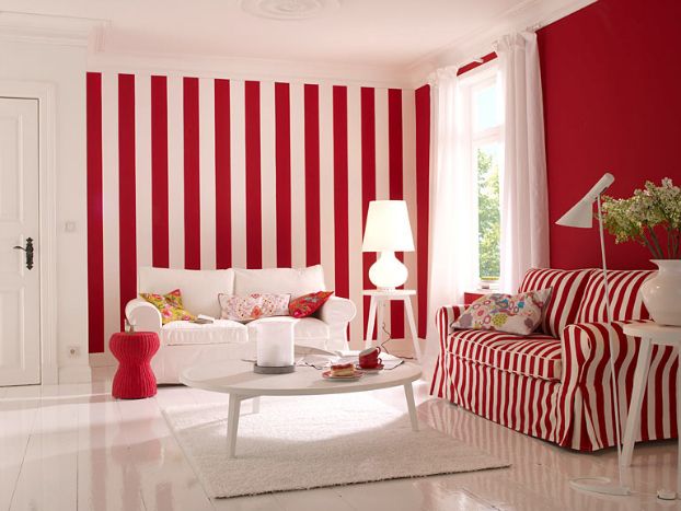 a living room with red and white stripes on the walls, couches, coffee table and lamp