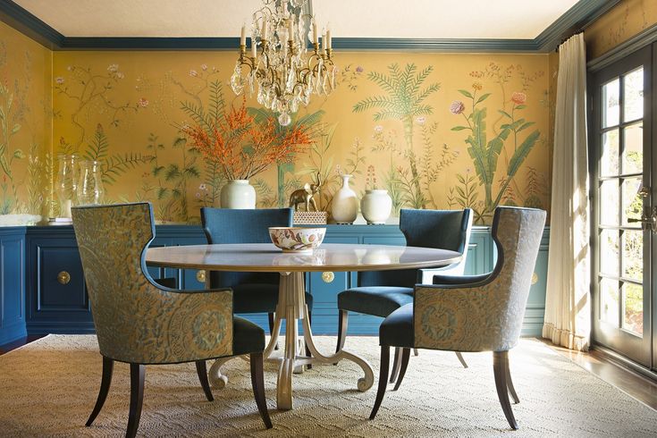 an elegant dining room with blue chairs and yellow wallpaper, chandelier above the table