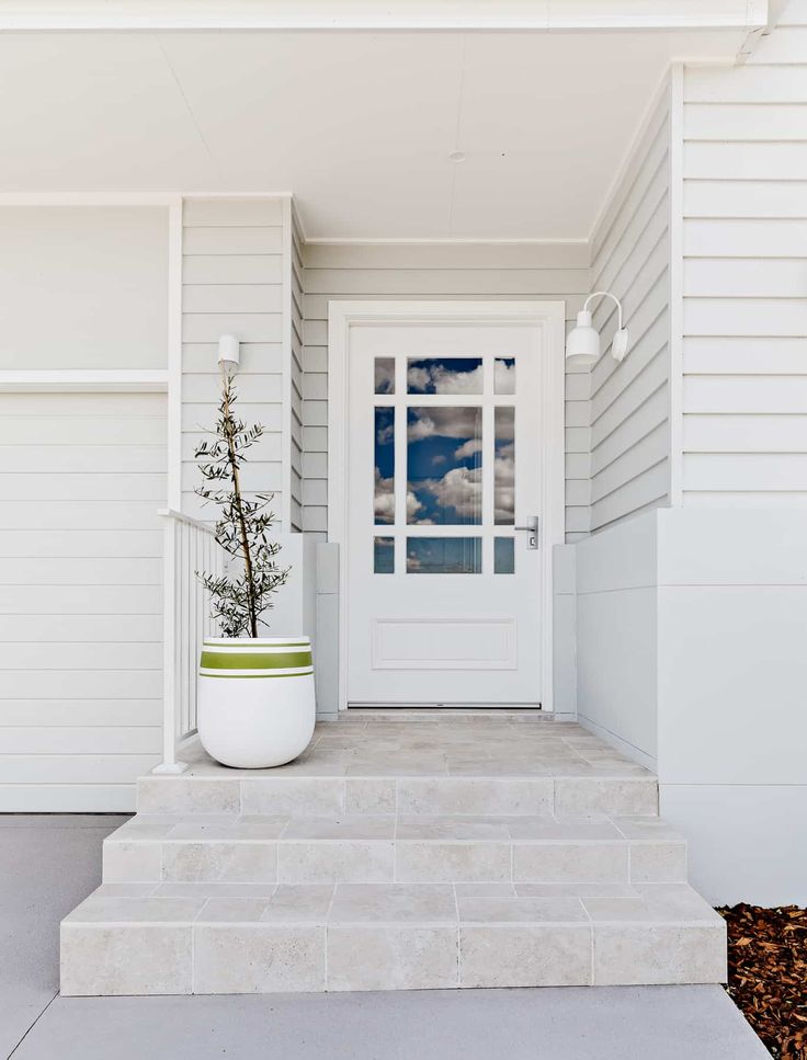 a white front door with a potted plant on the steps