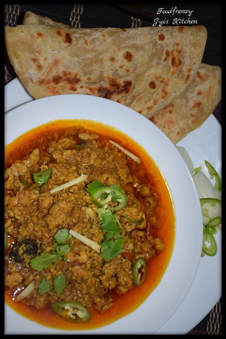 a white plate topped with meat and veggies next to pita bread