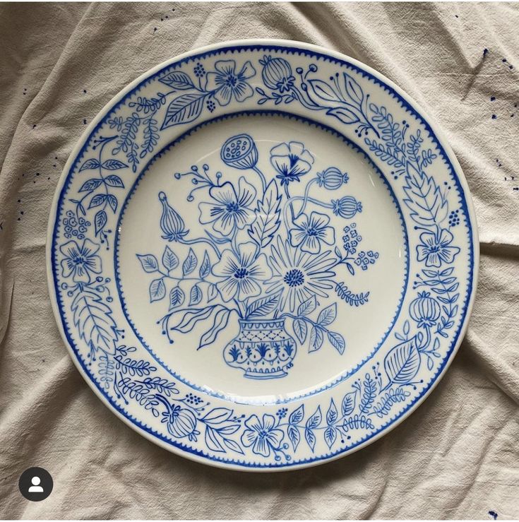 a blue and white plate sitting on top of a cloth covered table next to a wall