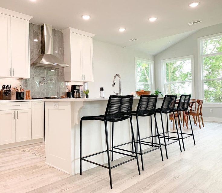 a kitchen filled with lots of counter top space and white cabinets next to a window