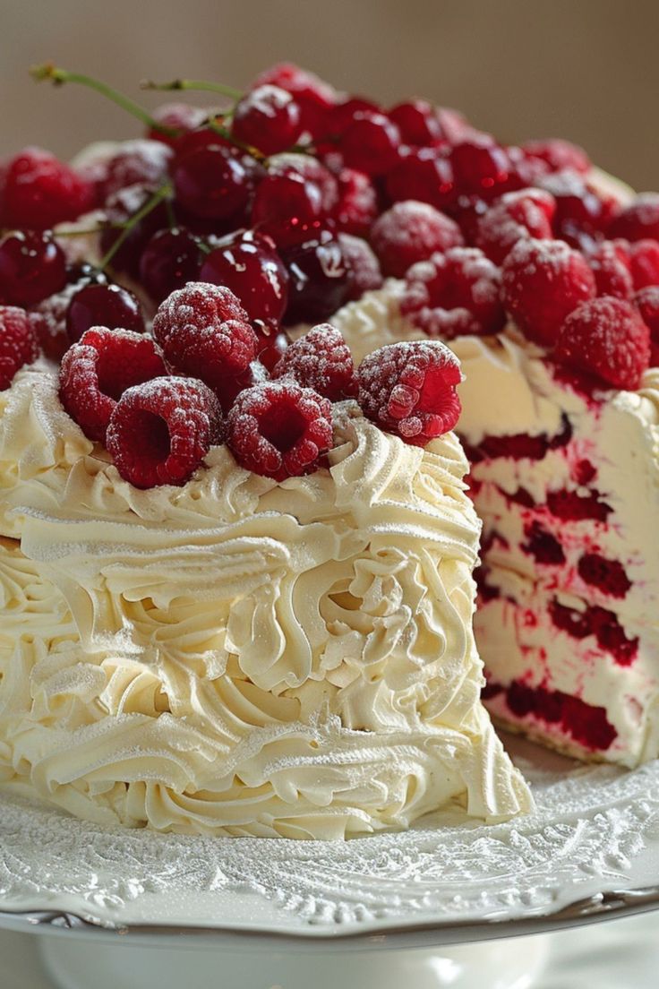 a cake with white frosting and raspberry toppings on top is sitting on a plate