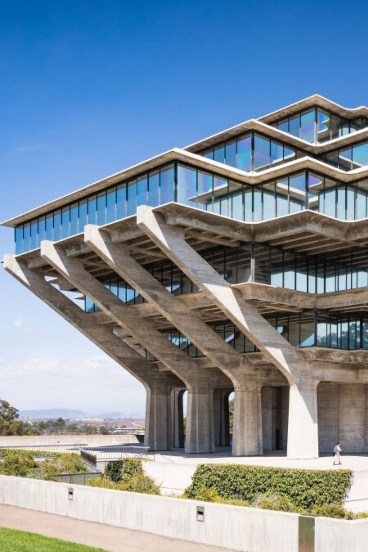 an unusual building with many windows on the top and bottom floor, in front of a grassy area