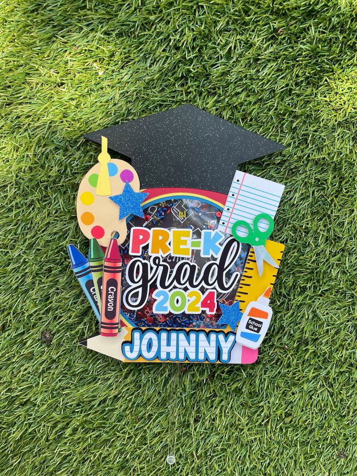 a graduate's cap and diploma laying on the grass with some school supplies in it