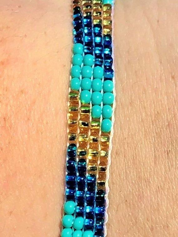 "Perfect for a pop of color! This turquoise \"skinny\" bracelet will charm your way through the day. Made using brilliant glass seed beads and premium nylon, these bohemian styled bracelets are dressed to impress and are a must-have every day accessory! Makes for a great birthday gift, Christmas gift, holiday gift, stocking stuffer, friendship bracelet and especially a \"just because\" gift for mom! Delicately handmade in Guatemala *Please note that all of our items are handcrafted and unique to Turquoise Friendship Bracelets With Tiny Beads For Summer, Summer Friendship Bracelets With Tiny Turquoise Beads, Turquoise Friendship Bracelet With Tiny Beads, Turquoise Summer Friendship Bracelet With Tiny Beads, Blue Bohemian Bracelets For Friendship, Bohemian Turquoise Friendship Bracelets With Spacer Beads, Hand-strung Turquoise Beaded Bracelets For Summer, Bohemian Braided Bracelets With Turquoise Round Beads, Turquoise Bracelet Jewelry For Summer