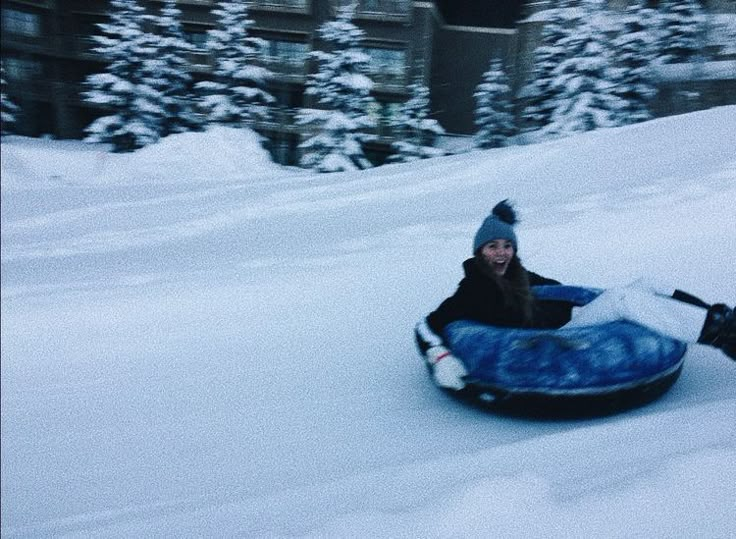 a woman is sledding down a hill in the snow