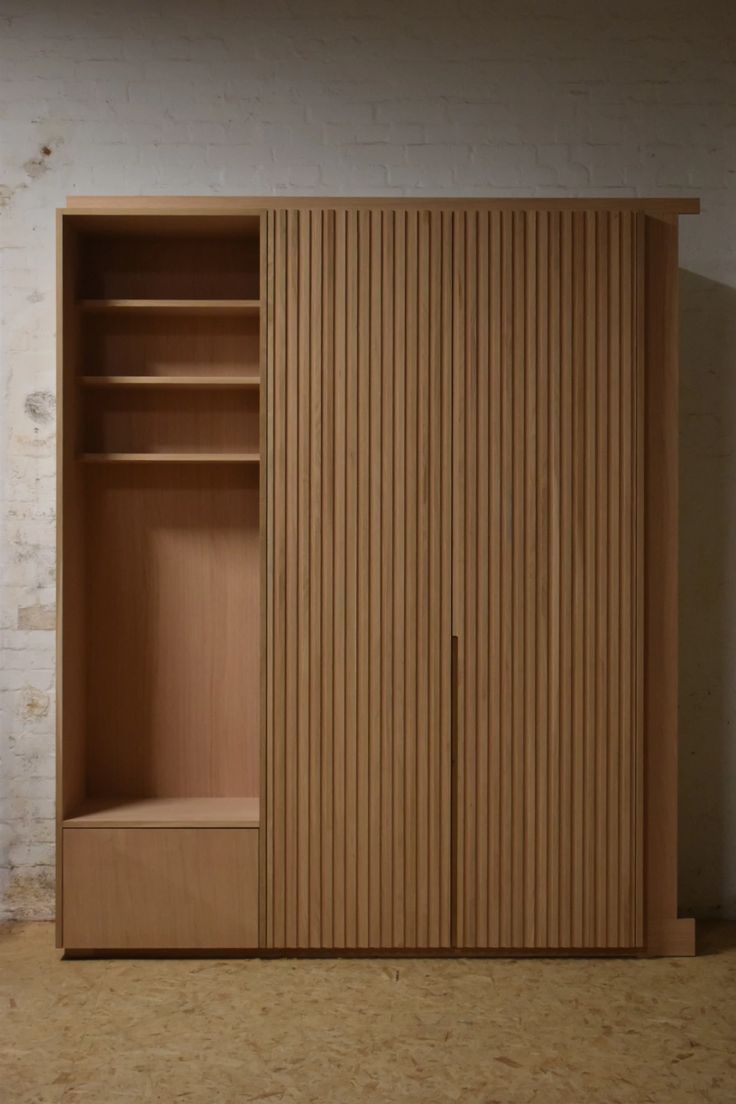 an empty closet with wooden doors and shelves on the wall next to a brick wall