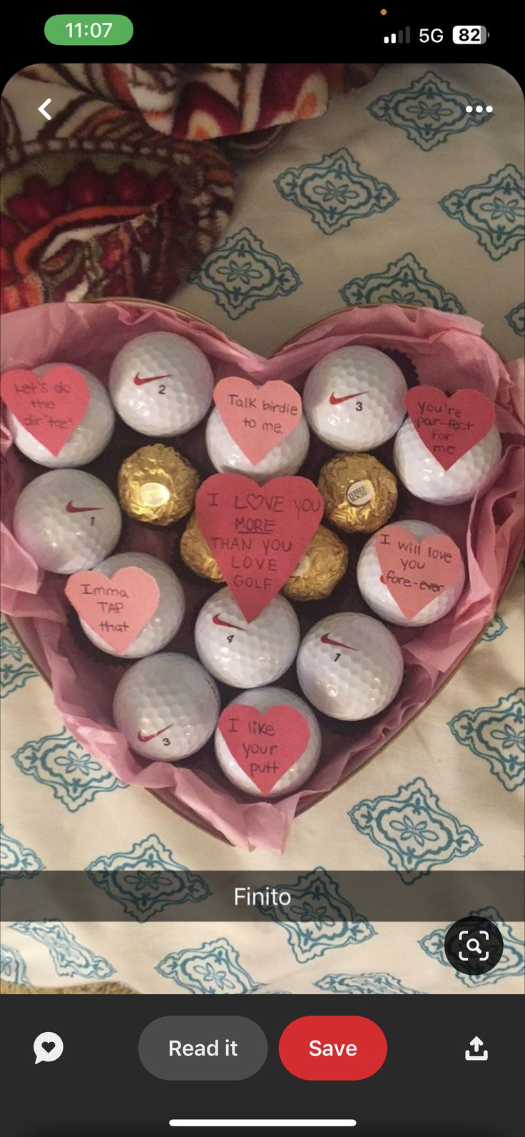 a heart shaped box filled with lots of golf balls and chocolates on top of a bed