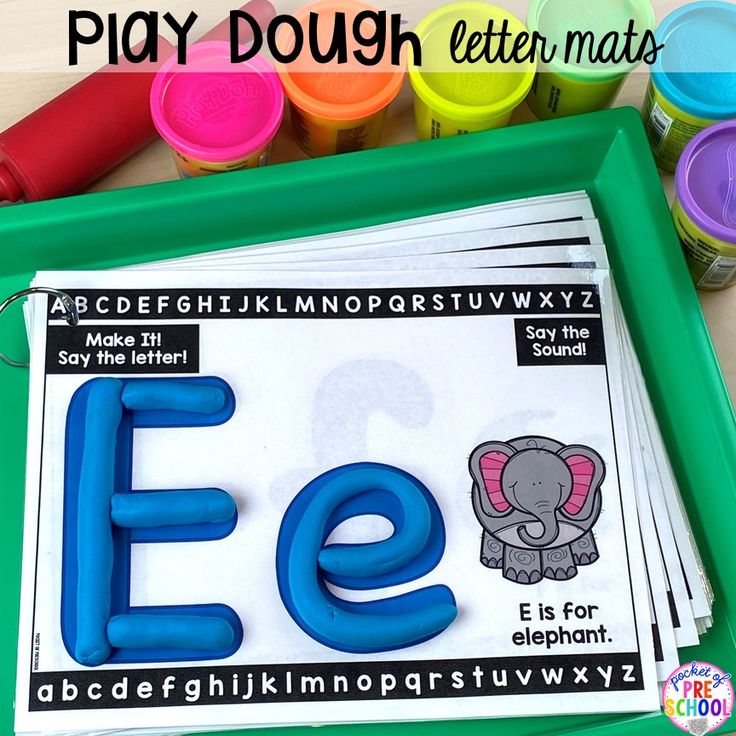 a green tray with letters and an elephant on it next to some crayons