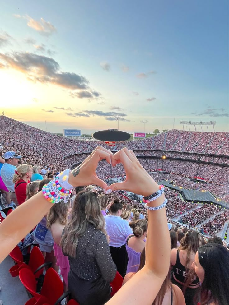 two hands making a heart shape in front of a large crowd at a sporting event