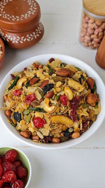 a white bowl filled with fruit and nuts next to other bowls full of dried fruits