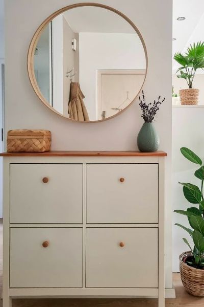 a white dresser with a mirror and potted plants