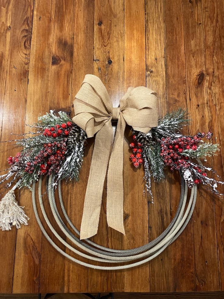 a christmas wreath on top of a wooden floor next to a metal circle with ribbon