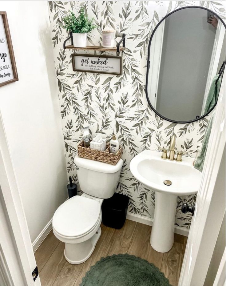 a white toilet sitting next to a sink in a bathroom under a mirror above a vanity