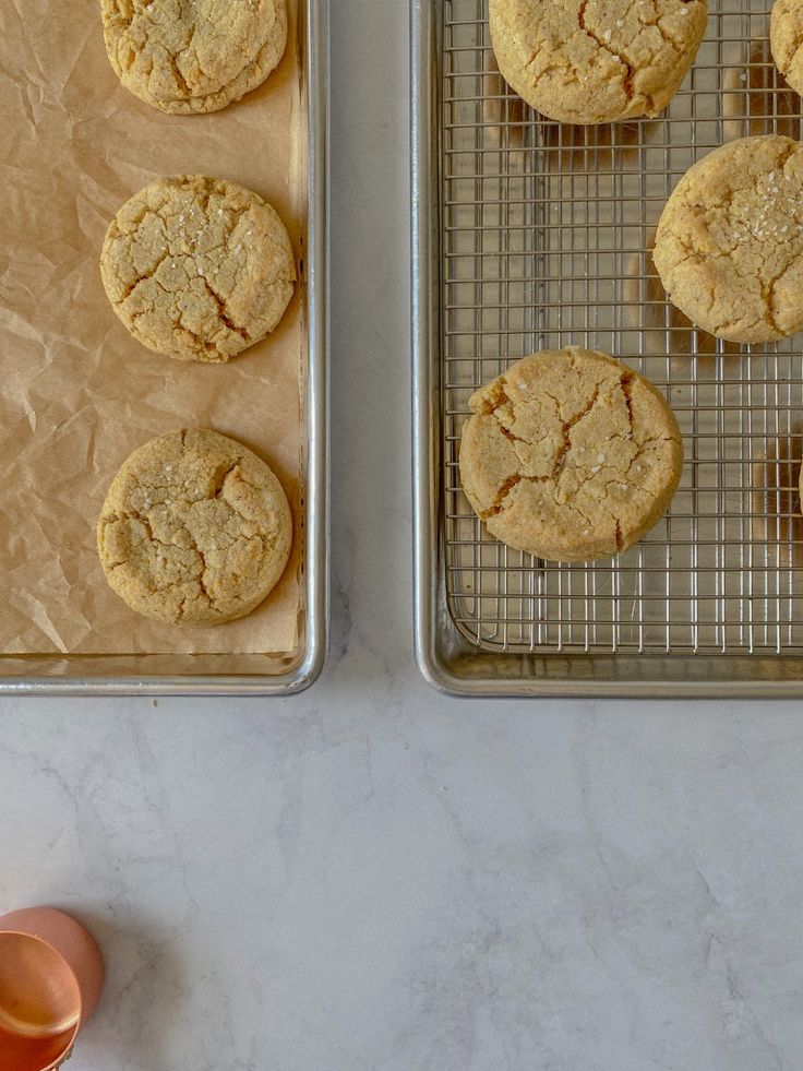 cookies cooling on the rack next to an orange glass and two trays filled with them