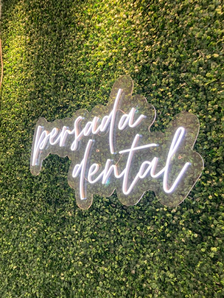 a neon sign that says persuda dental on the side of a green wall