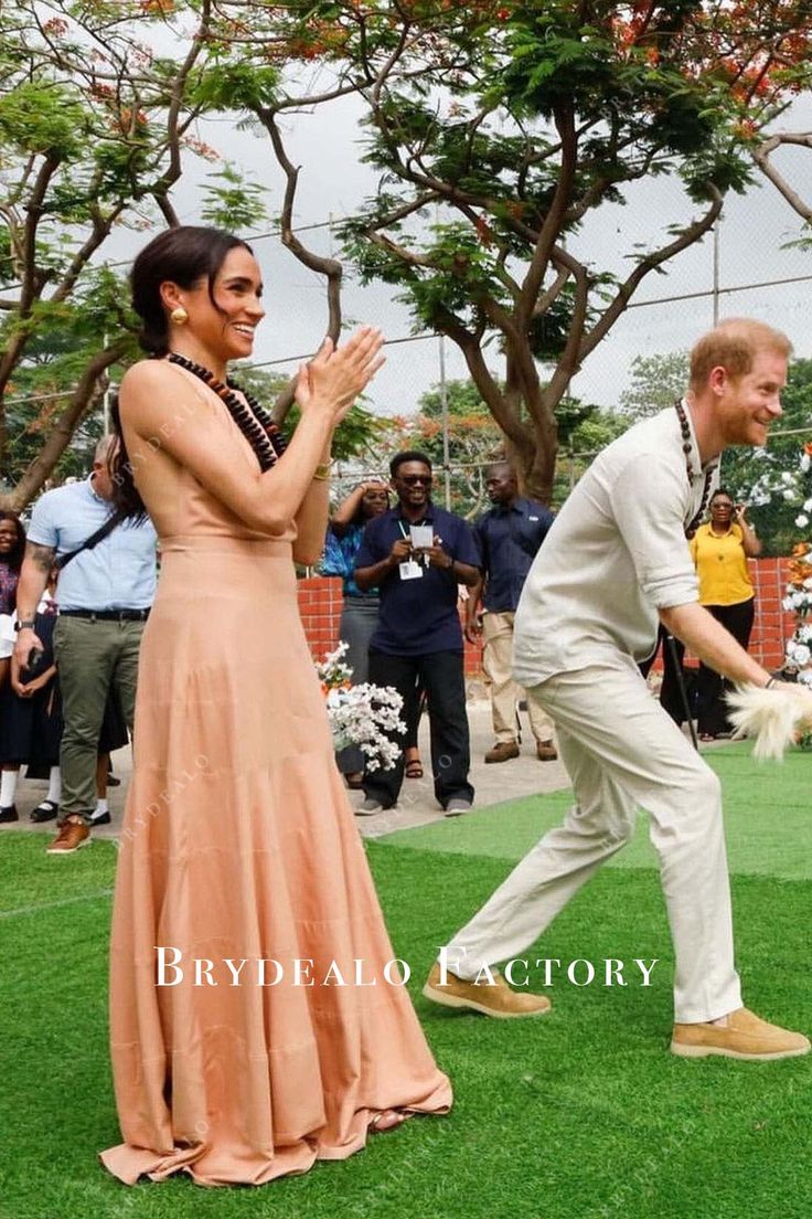 a man and woman in formal wear dancing on grass