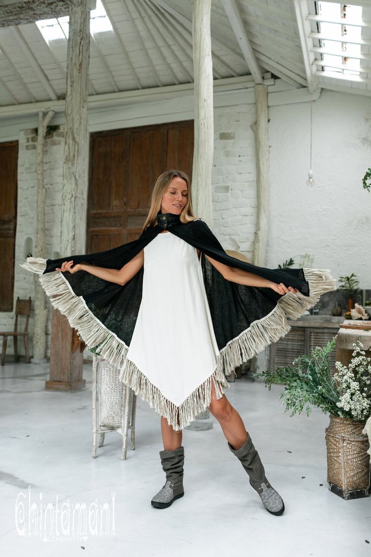 Cotton Open Back Poncho is a very original designer garment to compliment your boho outfit on a cool summer evening. High cotton canvas collar is reminiscent of elegant XIX century lady cloak, while long gorgeous linen fringe on the hemline brings an ultimate boho touch to the piece. The back of the poncho is open and also decorated with the statement fringes of our Alma Libra collection. It is made of 100% natural raw and very soft cotton. In hot climate you can wear this Poncho with our open b Black Bohemian Poncho For Summer, Bohemian Black Summer Poncho, Summer Bohemian Black Poncho, Black Bohemian Shawl For Fall, Bohemian Fringe Cape Poncho, Black Bohemian Shawl For Spring, Black Bohemian Poncho One Size, Black Bohemian Poncho Shawl, Black Shawl Poncho For Festival