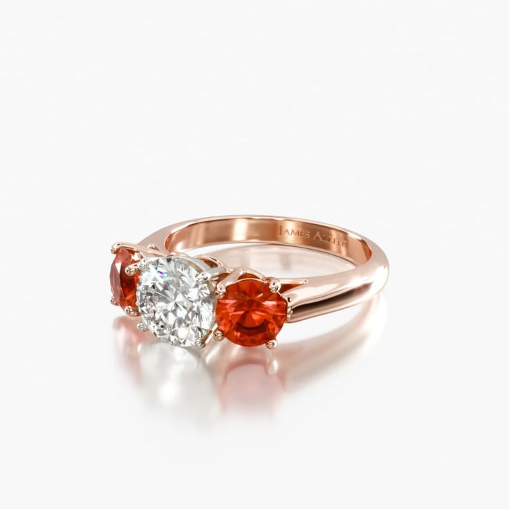 14K Rose Gold Three Stone Round Ruby Engagement Ring. This stunning ladies engagement ring features two beautifully matched round brilliant cut rubies as an accent to the exquisite diamond of your choice. All three stones are set in a wire basket with a slightly rounded, airline shank. Center diamond is flanked by round gemstones measuring 4.5mm. Rose Gold Ruby And Diamond Ring, Diamond And Ruby Rings, Lab-created Ruby Diamond Ring With Prong Setting, Anniversary Ruby Ring With Moissanite In Round Cut, Anniversary Ruby Ring With Round Cut Moissanite, Ruby Ring With Prong Setting And Moissanite, Promise Ruby Ring With Prong Setting, Rose Gold Ruby Wedding Ring With Prong Setting, Lab-created Ruby Diamond Ring With Brilliant Cut