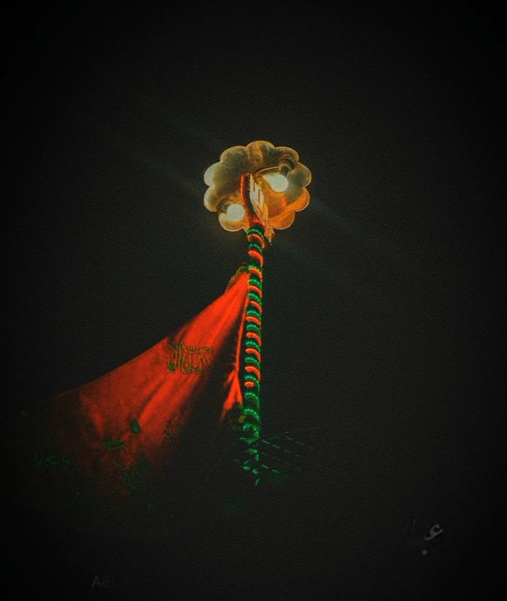 a tall red and green pole with a light on it's top at night