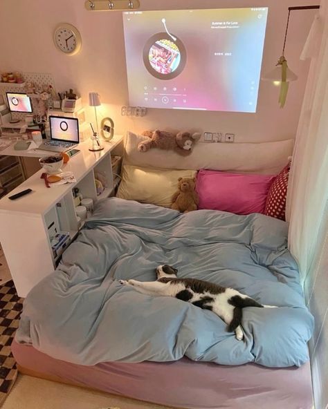 a cat laying on top of a bed in a room with a projector screen