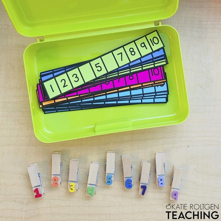 a green container filled with lots of different colored pencils next to some sort of numbers