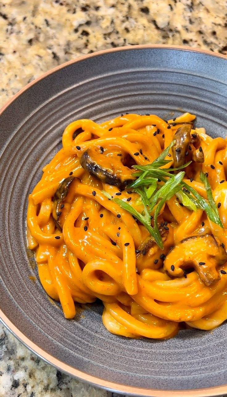 a plate of food with noodles and vegetables on it sitting on a marble counter top