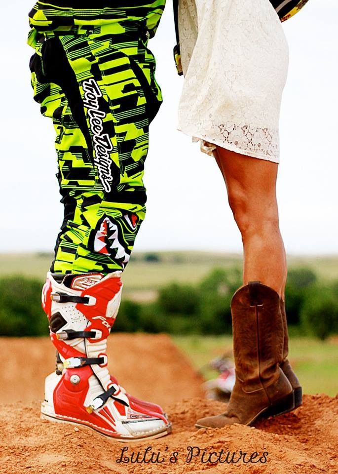 the legs and feet of a person in cowboy boots on dirt ground with grass behind them