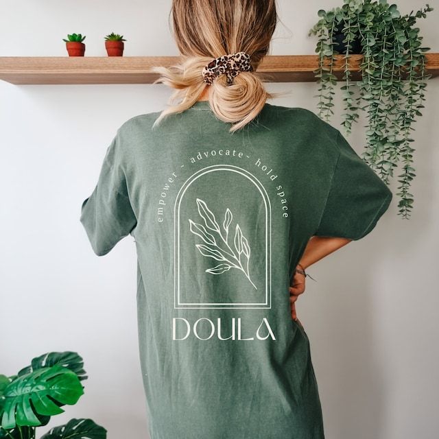 a woman wearing a green t - shirt with the words doula printed on it