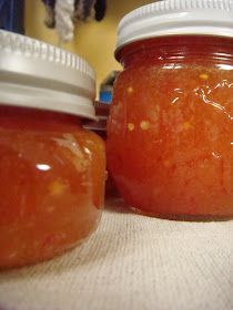 two jars filled with red sauce sitting on top of a white cloth covered tablecloth