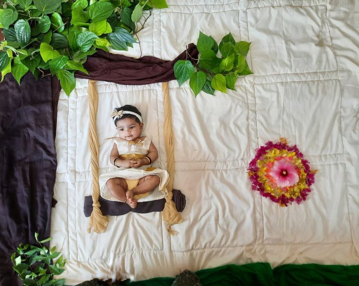 a baby is sitting on a swing in the middle of a bed with green leaves