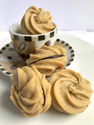 three cupcakes sitting on a plate next to a coffee cup