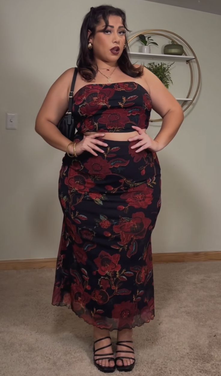 a woman in a black and red dress posing for the camera with her hands on her hips