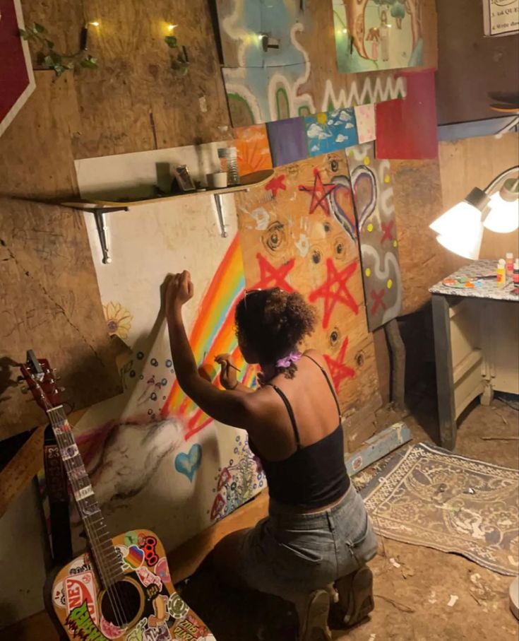 a woman is painting on the wall with her guitar