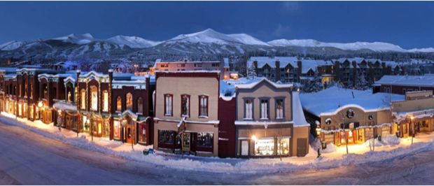 an aerial view of a town in the mountains at night with snow on the ground