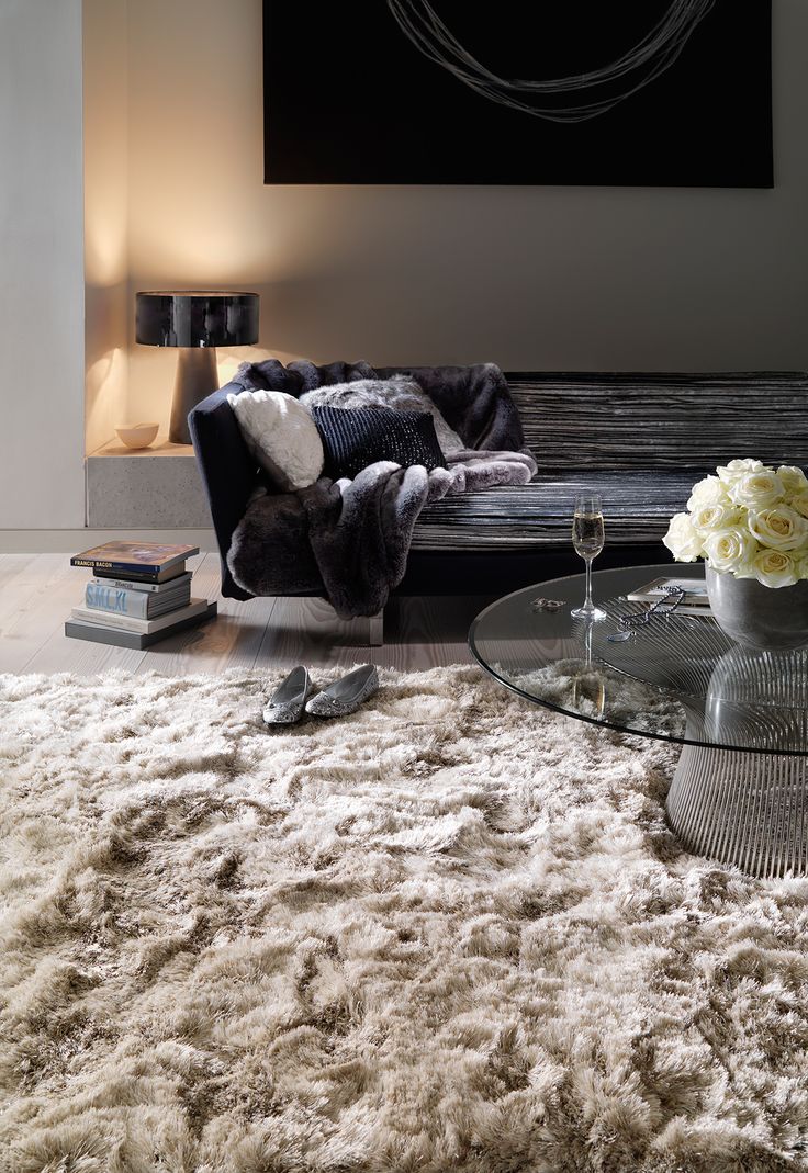 a living room filled with furniture and a large painting on the wall above it's glass coffee table