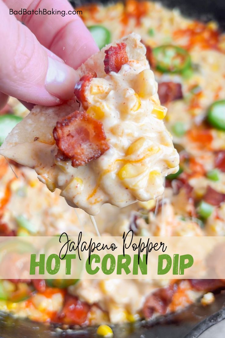 a hand holding up a piece of hot corn dip from a skillet with the words jalapeno pepper hot corn dip on it