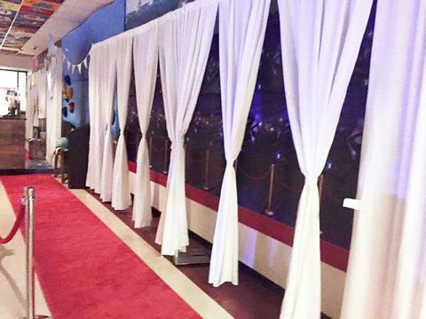 a red carpeted hallway with white drapes on the wall