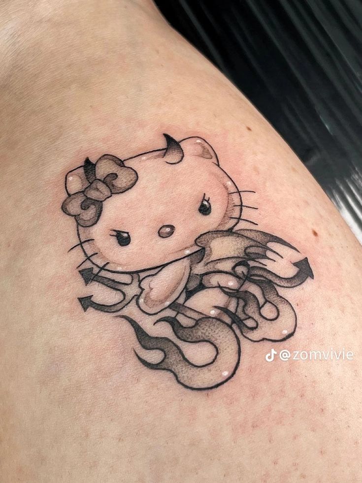 a hello kitty tattoo on the back of a woman's shoulder