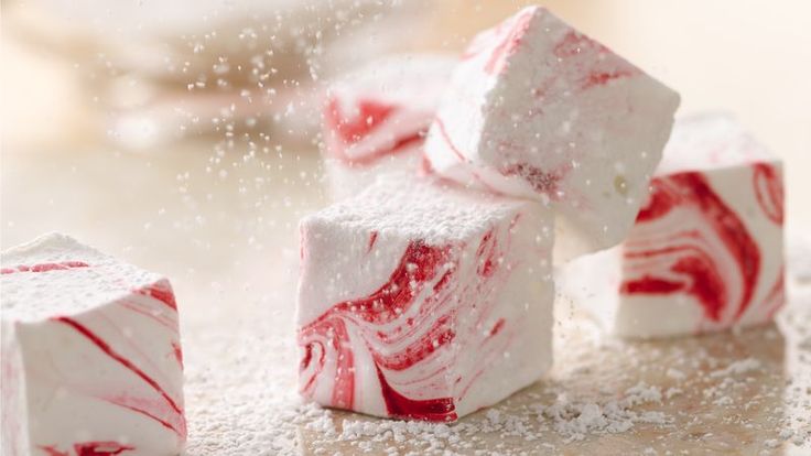 three white and red candy cubes sitting on top of a table covered in snow