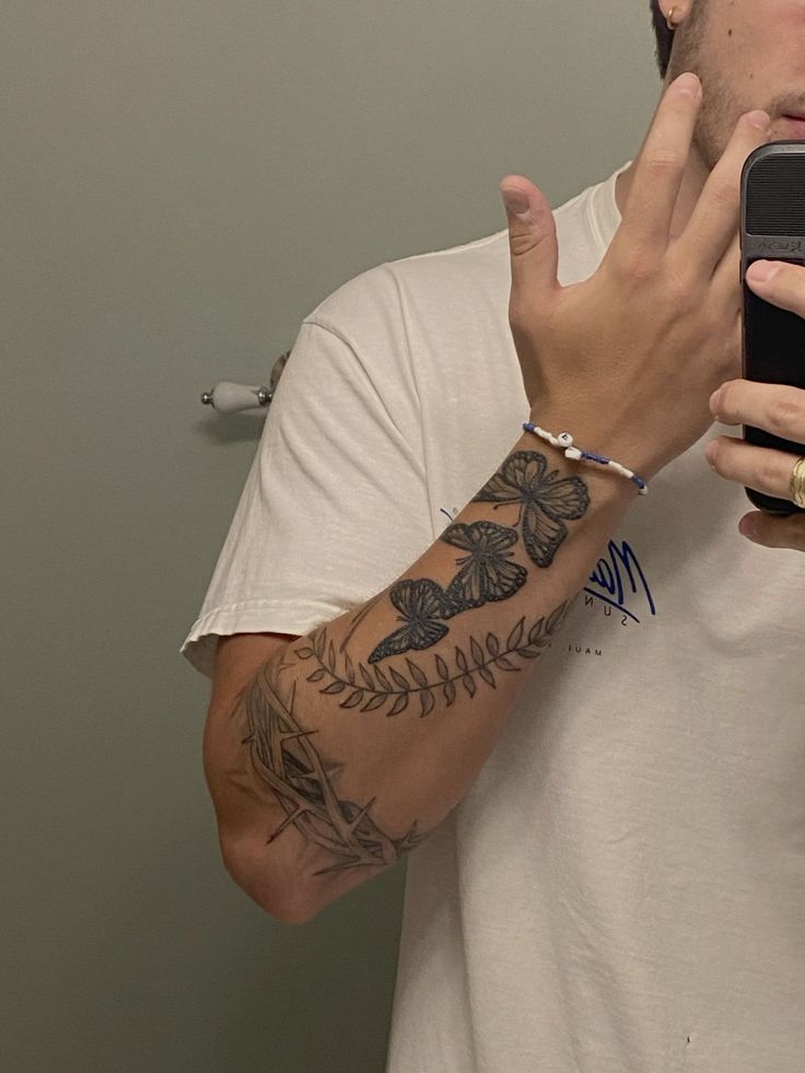 a man taking a selfie in the mirror with his cell phone and tattoos on his arm