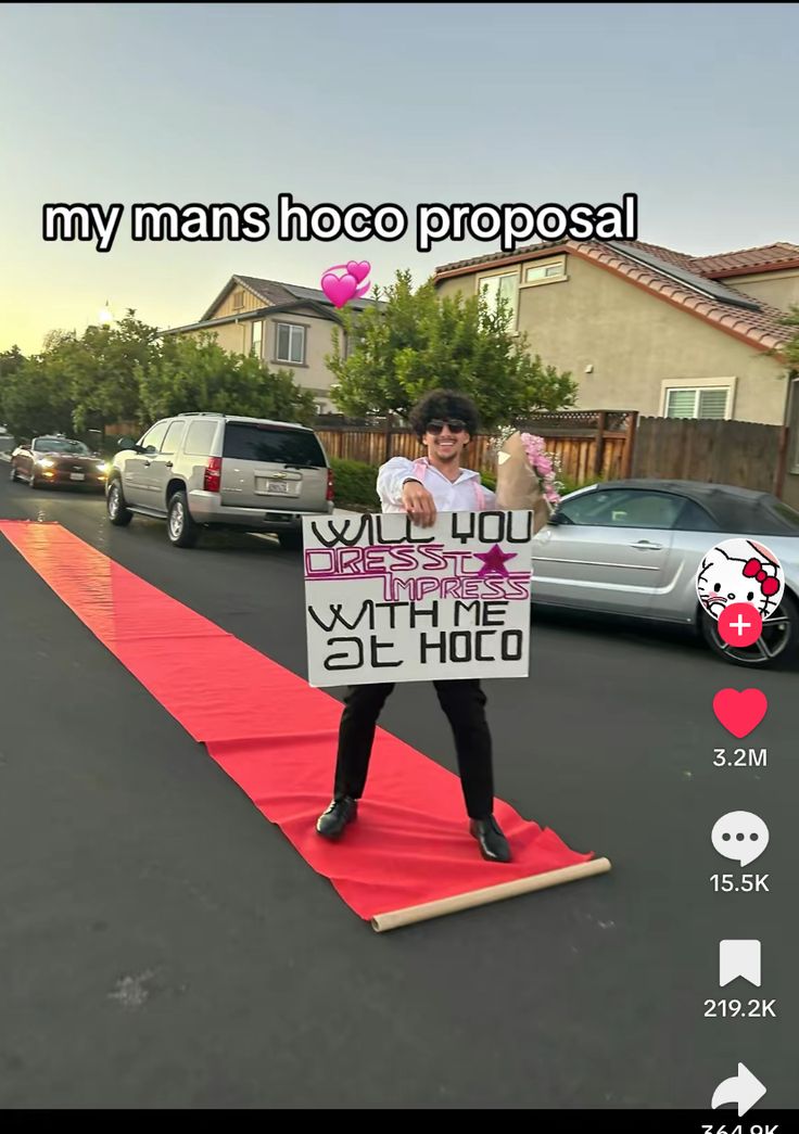 a woman holding a sign on top of a red carpet in the middle of a street