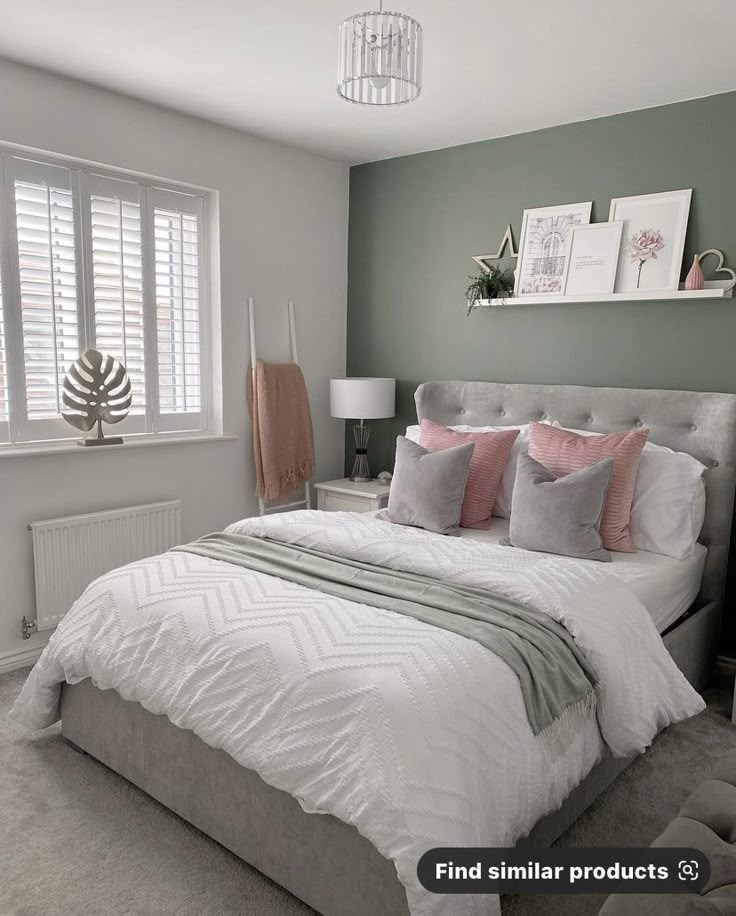 a bedroom with a bed, dresser and window covered in pink and gray pillows on it