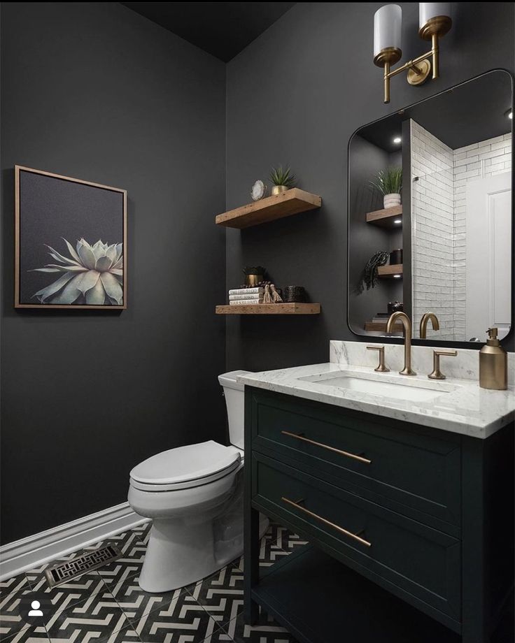 a black and white bathroom with gold accents on the vanity, toilet and mirror above it