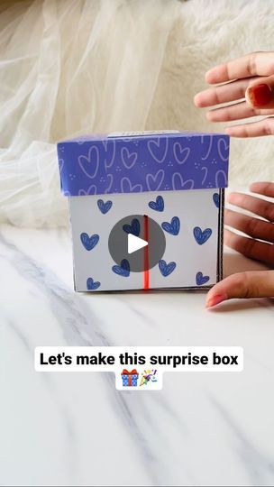 two hands holding a small box with hearts on it and the words let's make this surprise box