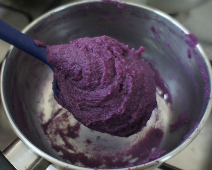 a purple substance in a metal bowl with a blue spoon